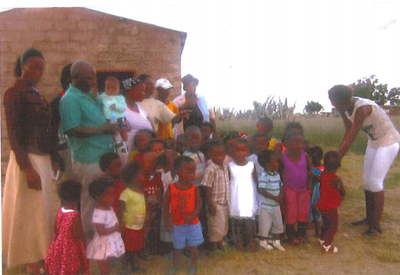 Volunteers and church committee members with some of the children in front of an outstation church that provides shelter to the children.